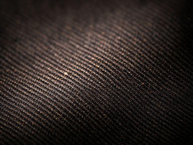 Köpergewebe mit feiner diagonaler Linie auf dunkler Naturfaser, aufgenommen in naher Detailansicht